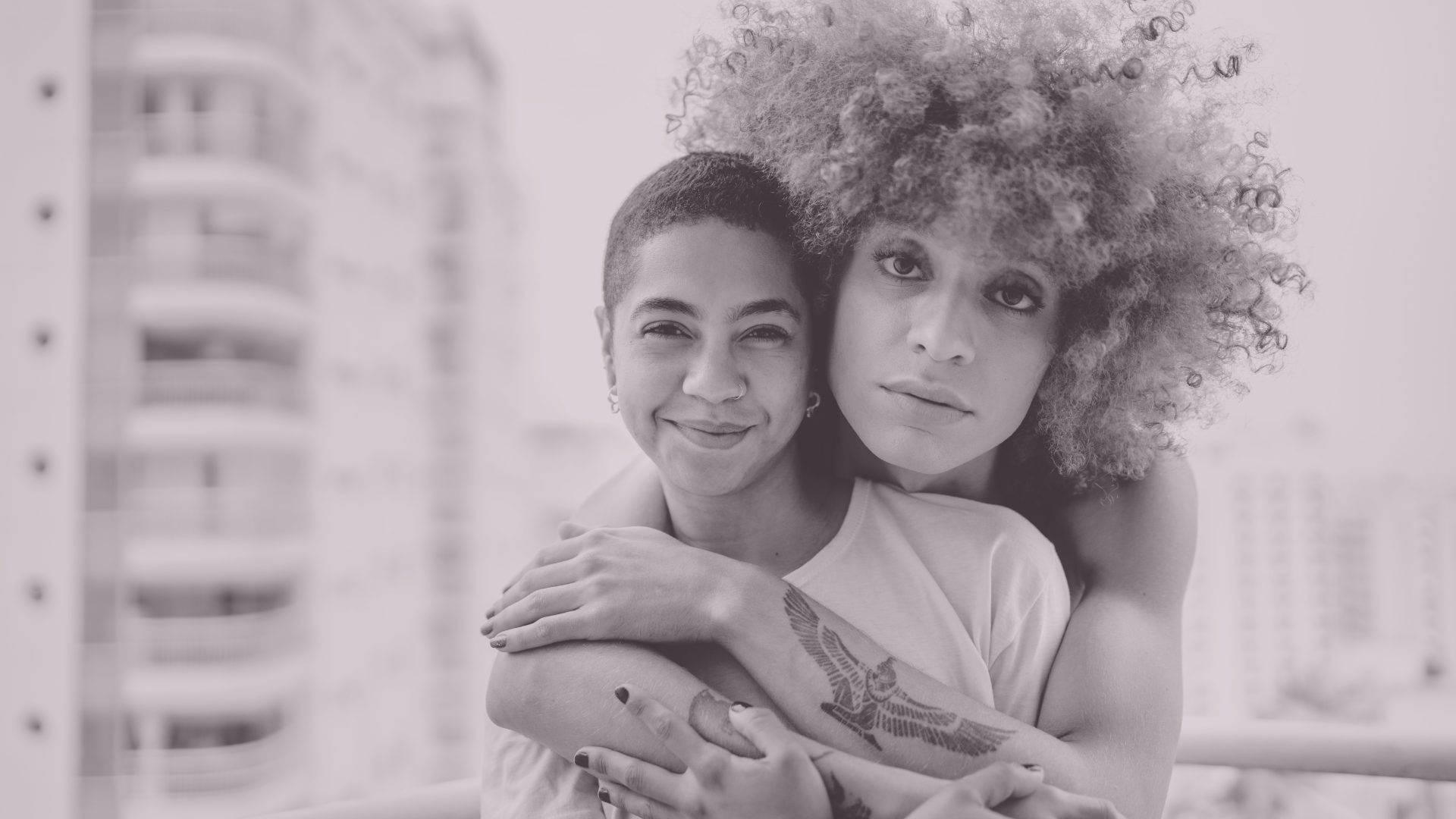 Two people embracing in front of a window.