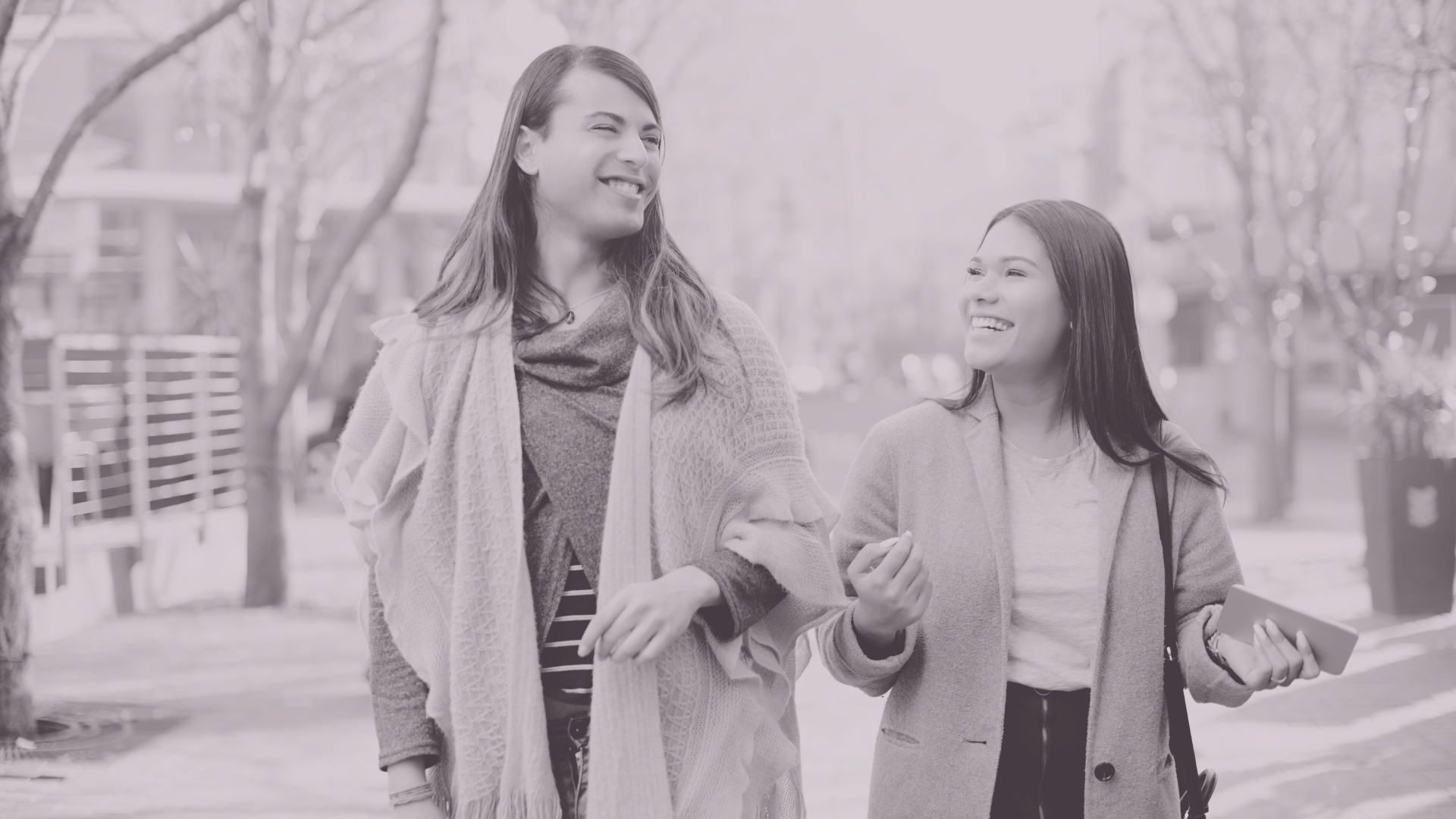 Two people, smiling, walking, looking at each other.